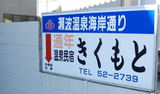 瀬波温泉海岸通りに立つ温泉民宿きくもとの看板